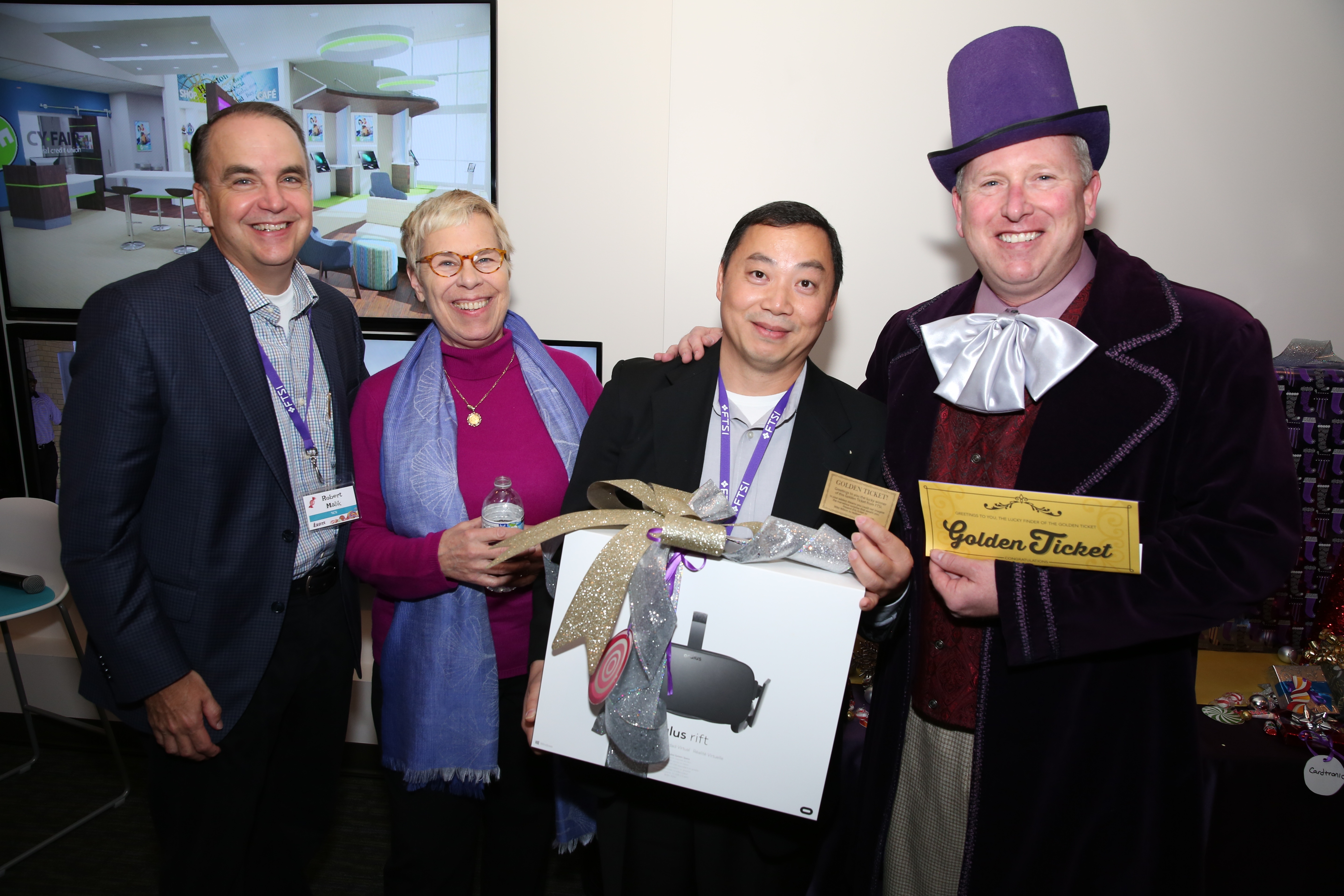 Four people dressed in Willy Wonka inspired clothing holding prizes and a golden ticket